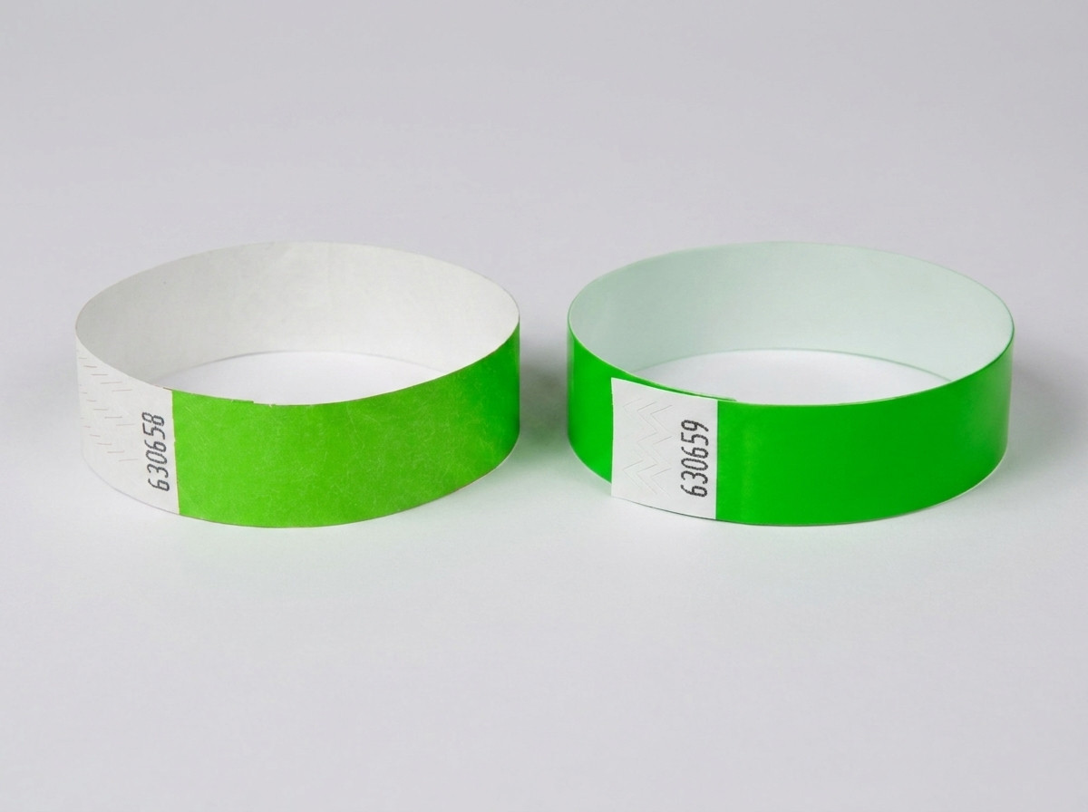 Vergelijking van een wit Tyvek-polsbandje met bedrukte streepjescode en een gekleurd identificatiepolsbandje met streepjescode naast elkaar op een festivaltafel